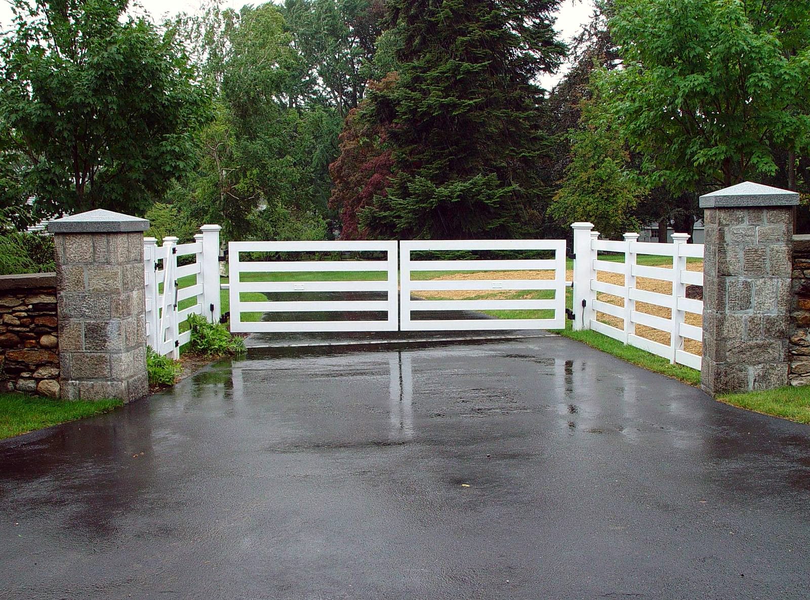 Simple white wooden ranch gate with stone pillars