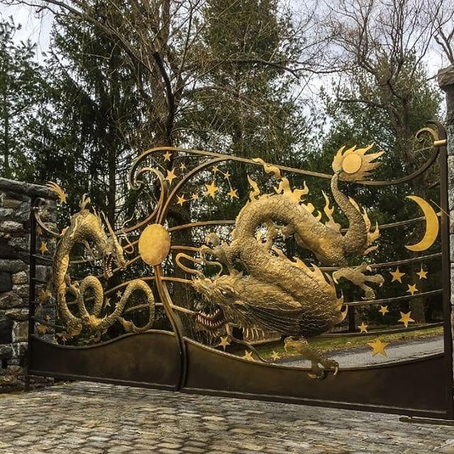 ornate mythological dragon with stars and moon on a large metal driveway gate