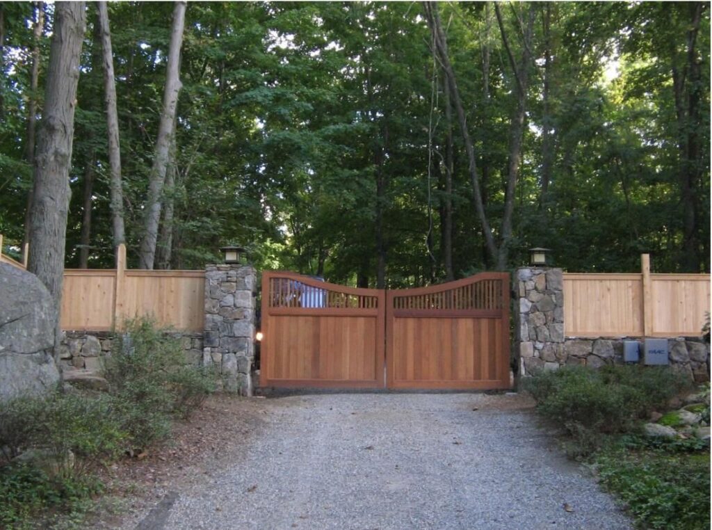 Automated Wooden Privacy Gate with Stone Pillars and Fencing