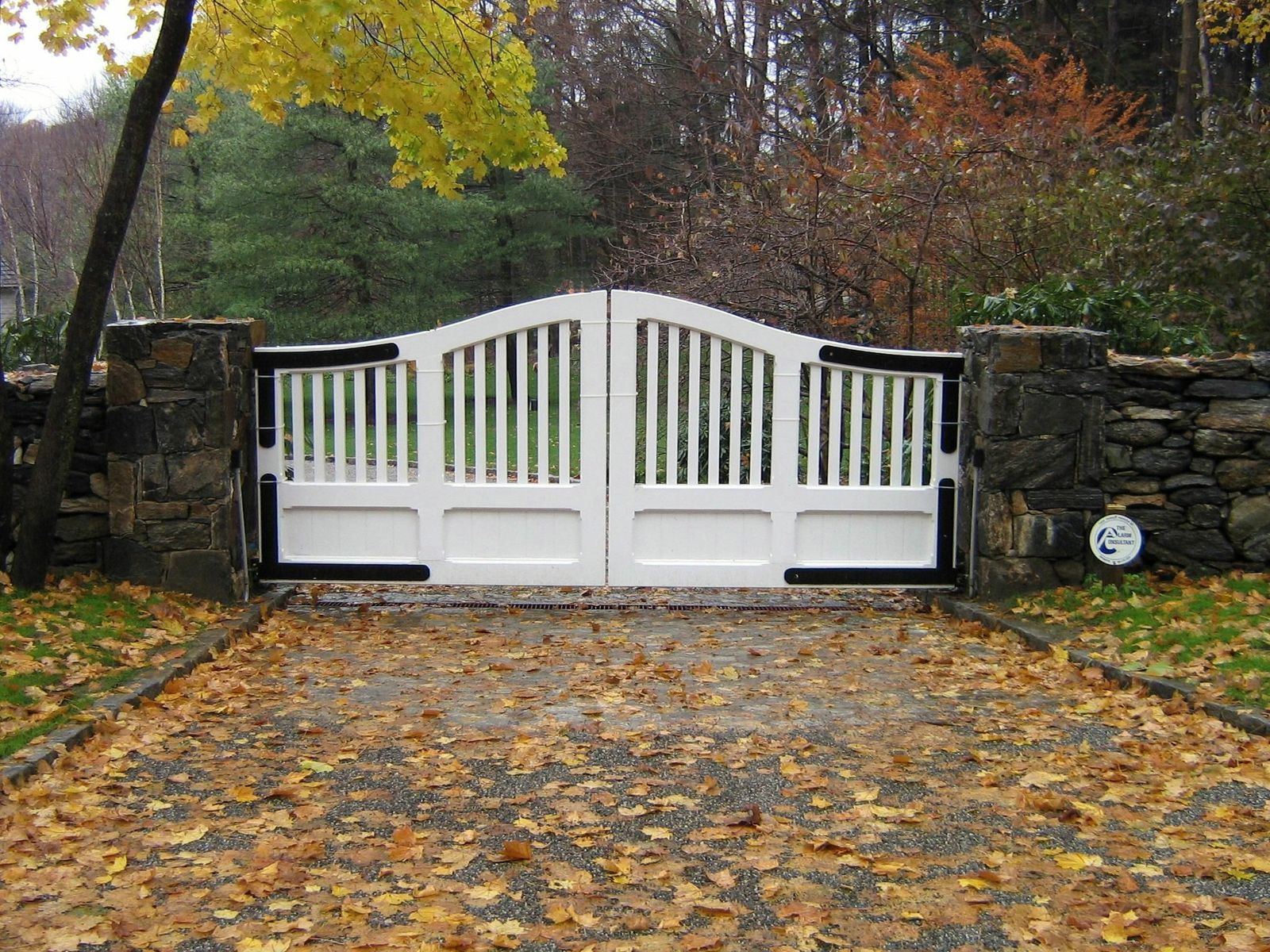 white gate with black metal trim and stone pillars