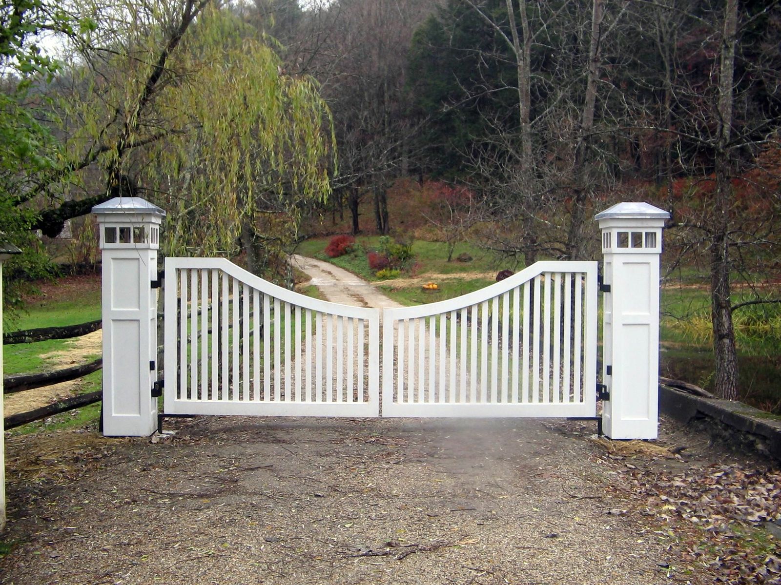 driveway gate lighting on the posts of a white wooden gate