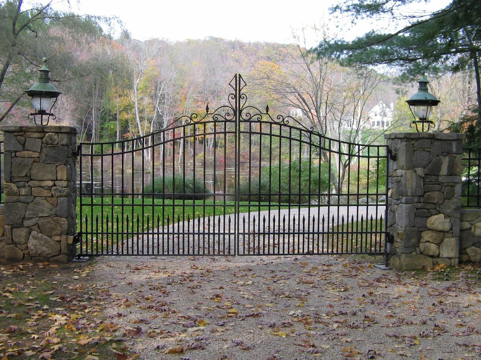 iron lamps on stone pillars for a large metal driveway gate