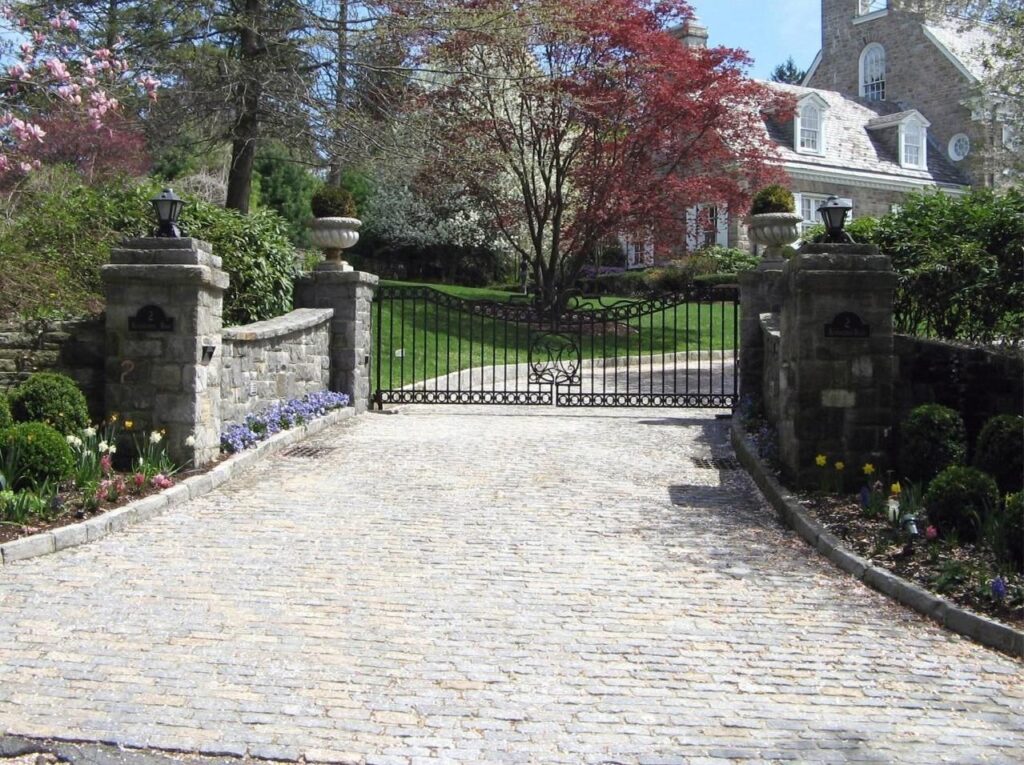 Ornate Metal Driveway Gate with Stone Pillars and Decorative Urns