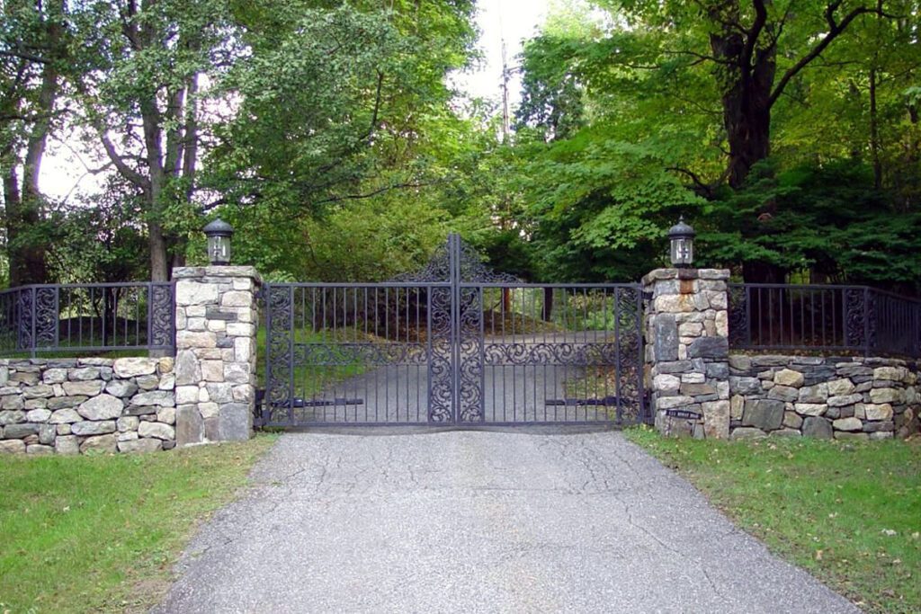 Lighting and Stone Pillars on an Ornate Metal Driveway Gate