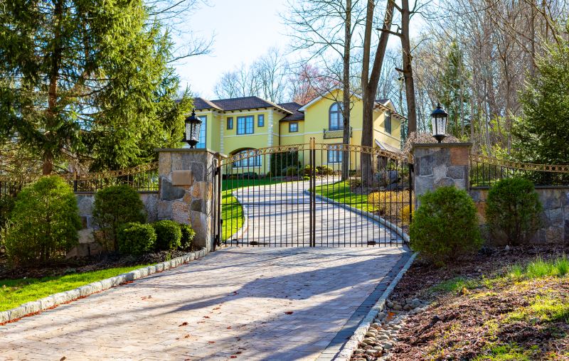 A Wrought Iron Fence Sits Between Two Warm Colored Stone Columns.
