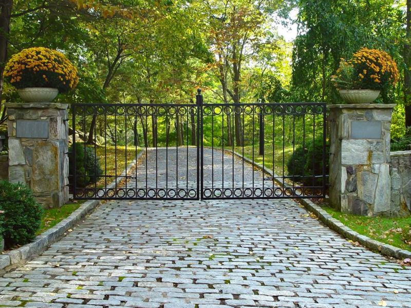 Wrought Iron Gate with Circle Design and Planters on Stone Pillars.