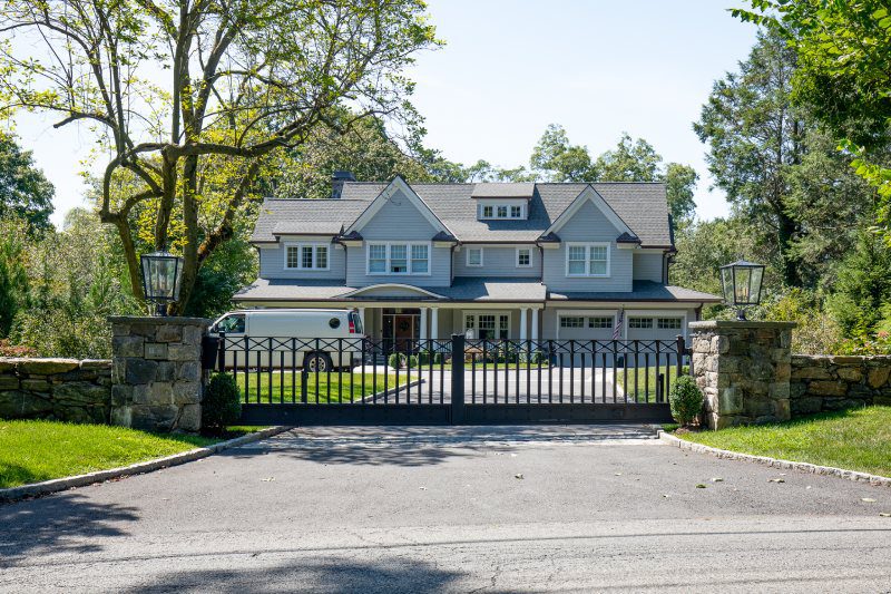 A House Behind A Black Metal Gate With Stone Columns.