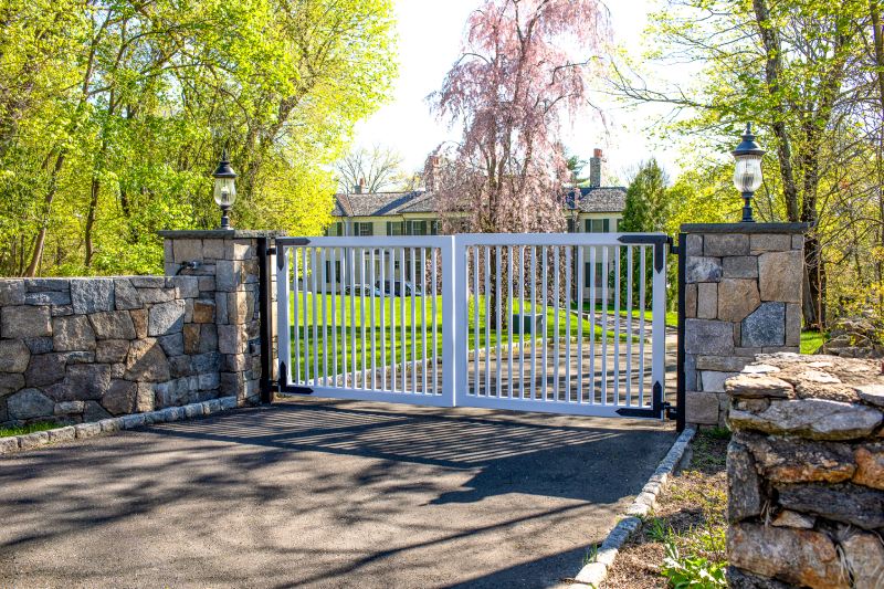 A White Wooden Gate Sits Between Natural Stone Columns with Lighting.