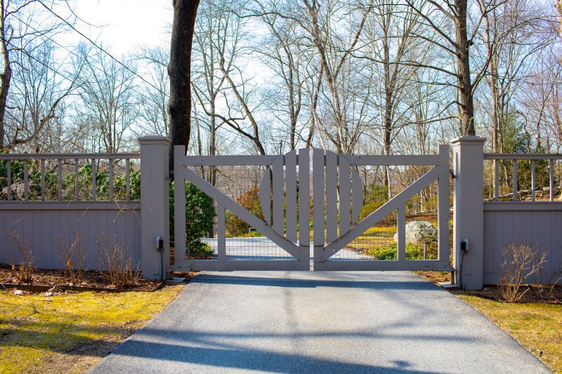 A White Gate with Several Different Paneling Designs, Including A Circle at the Center.