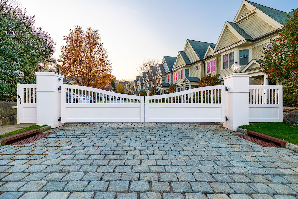front perspective of white community driveway gate with stone brick road