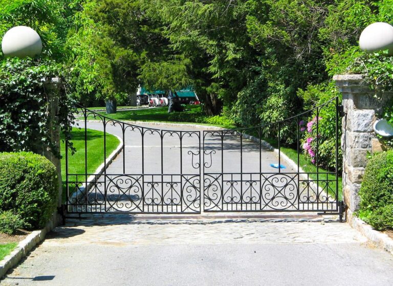 unique curved patterns in metal driveway gate with stone columns and orbs