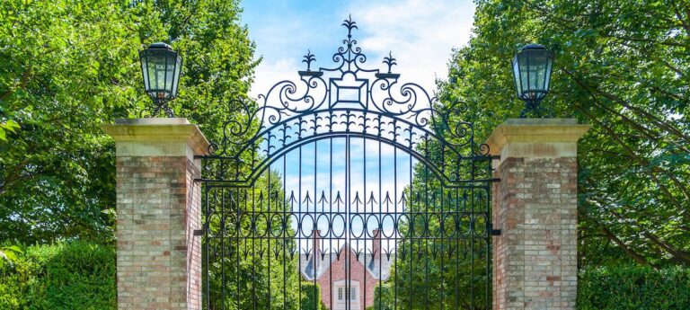Extra tall metal driveway gate with ornate decor and stone pillars