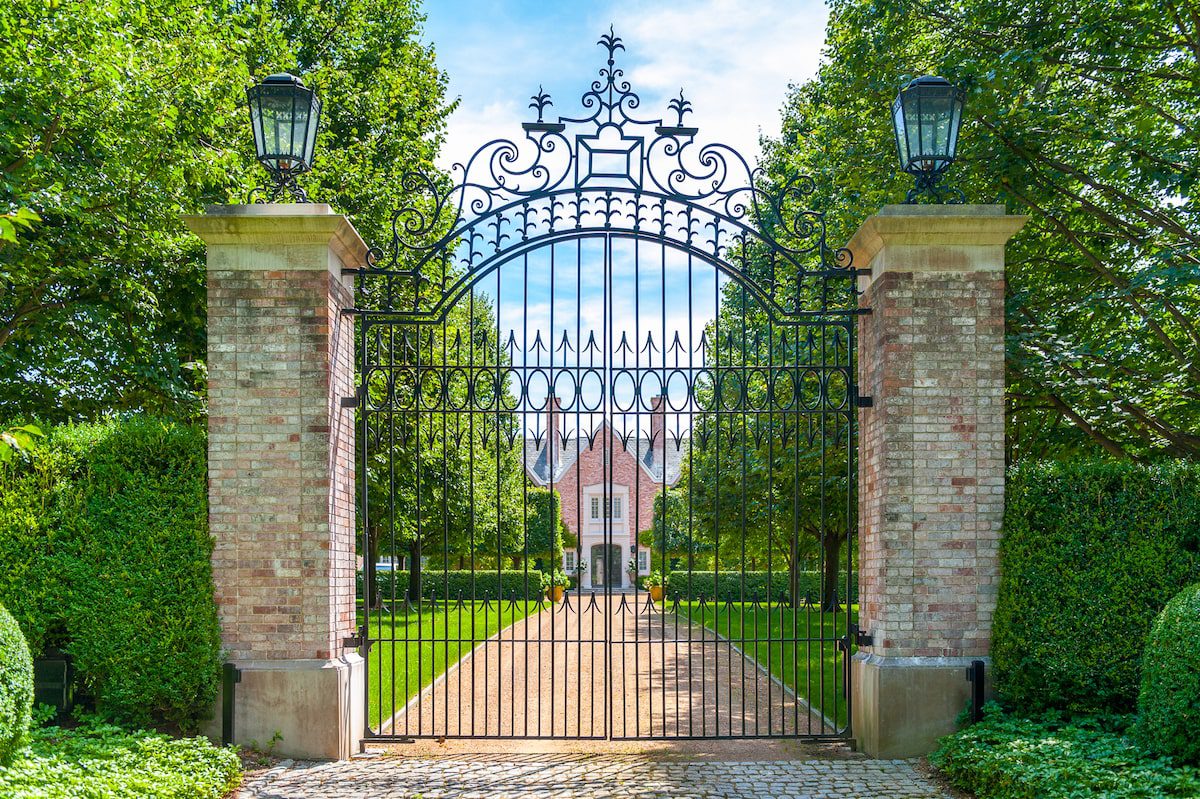 Extra tall metal driveway gate with ornate decor and stone pillars