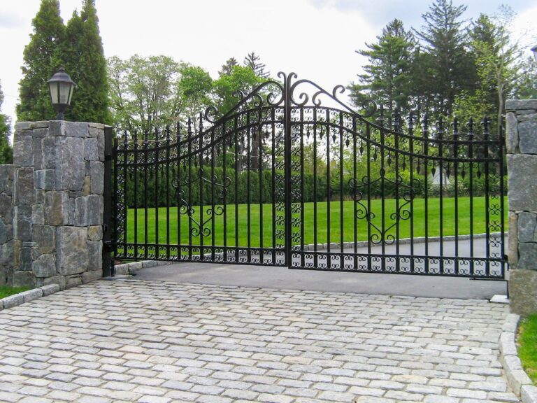custom iron gate with swirl patterns and gray stone columns with lanterns