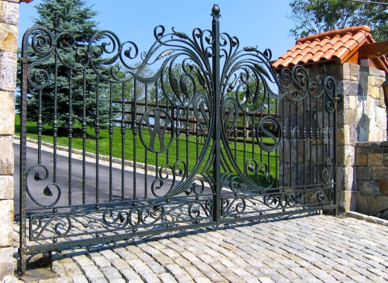 unique swirl and leaf design iron custom driveway gate with stone columns and pitched tops with shingles