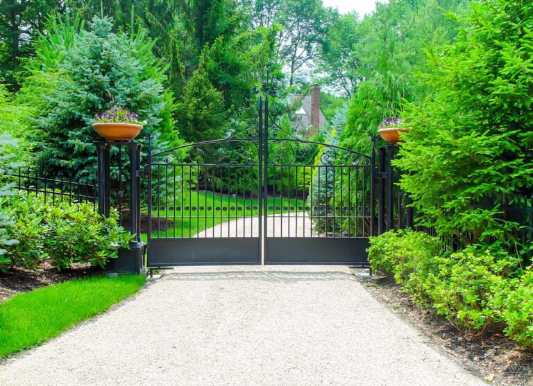 arched black metal swing gate with swirl designs and metal columns with ceramic planters