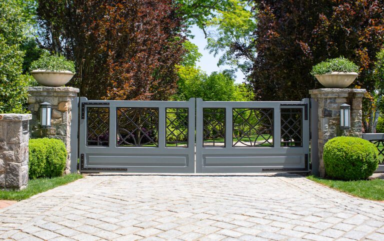modern composite and metal driveway gate with custom hardware and stone columns with planters