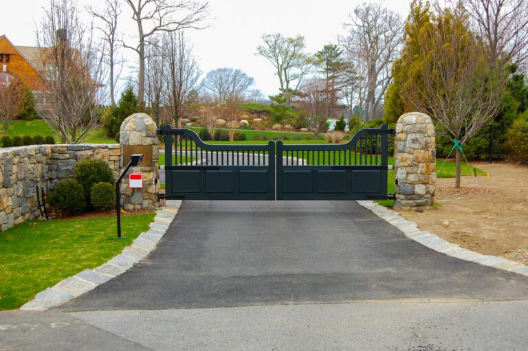 modern black composite driveway gate with rounded natural stone brick columns