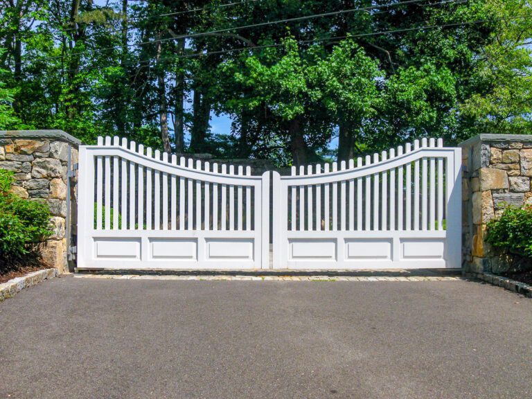 scalloped white picket composite driveway gate and stone pillars