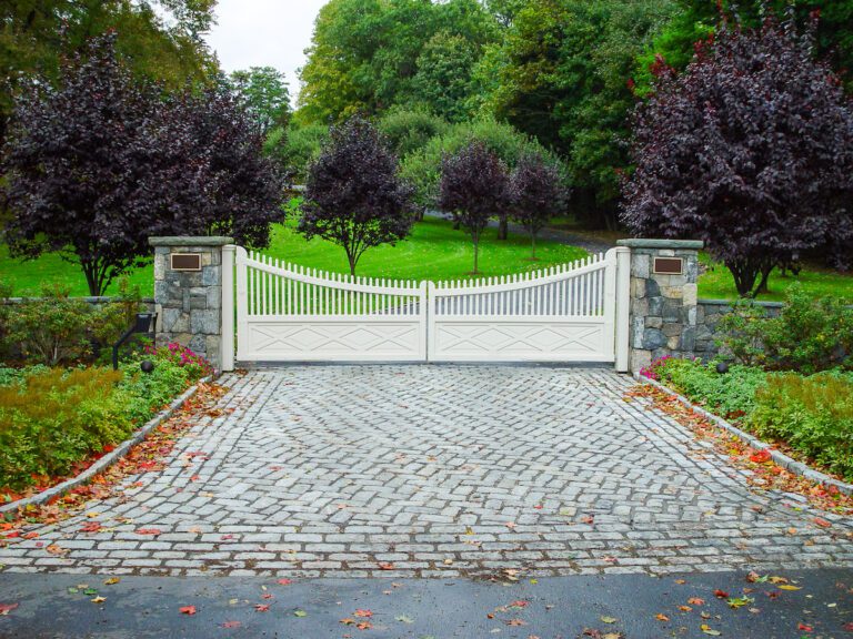 cream composite driveway gate with pickets and natural stone pillars