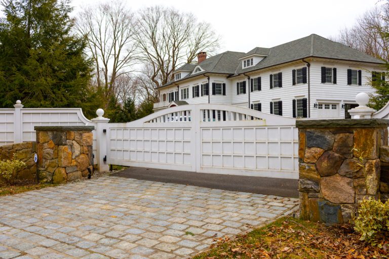 white arched composite driveway gate with natural stone pillars