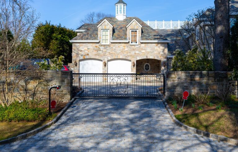 metal driveway gate with circular design and stone fencing