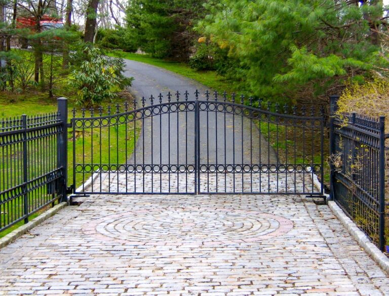 simple wrought iron driveway gate with finials and matching fencing