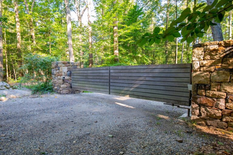 barn style swing wooden driveway gate with stone pillars