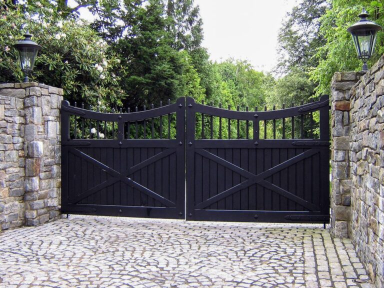 black wood driveway gate with stone apron