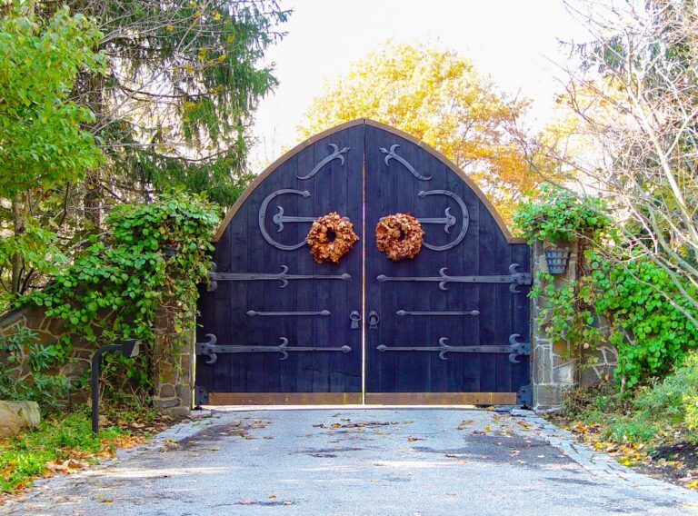 large arched blue wooden driveway gate with wreath decor