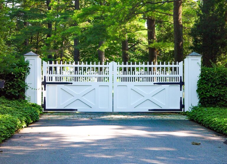 large white driveway gate with unique picket-inspired design and black hardware