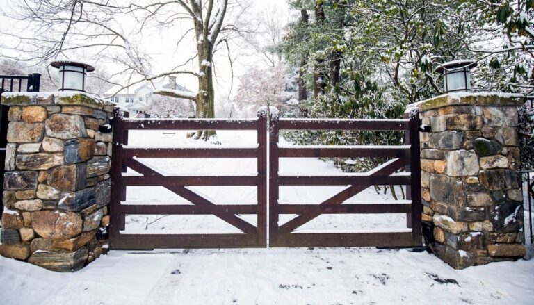 post rail style dark wood gate with stone columns in the snow