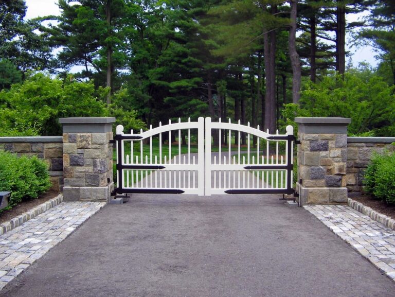 white driveway gate with unique picket inspired design and prominent custom hardware
