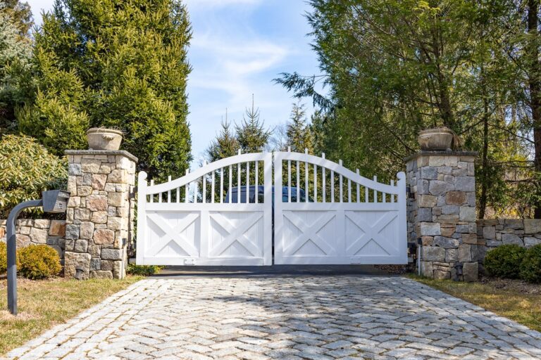 Wood driveway swing gate with cross design and stone apron