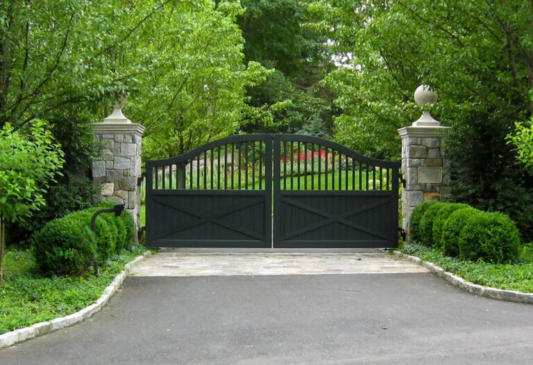 arched black wooden driveway gate with stone brick columns