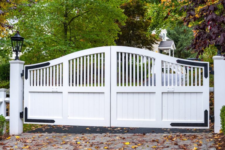 arched white wood driveway gate with black hardware and lanterns