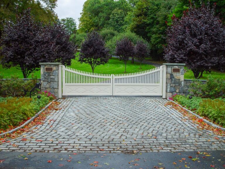 scalloped wooden driveway gate with pickets and stone columns with plaques