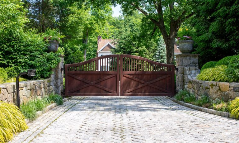 traditional ipe arched driveway gate with stone columns and urn planters