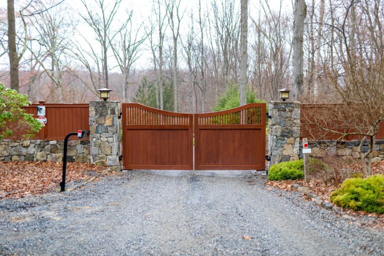 Mahogany scalloped driveway gate with matching fence and stone apron and entry pad