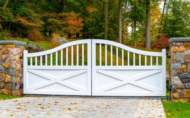 white wood gate with post rail inspired design and brick like natural stone columns