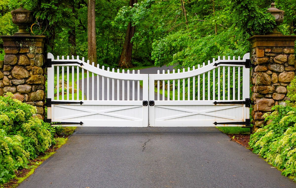 white scalloped wood gate with metal trim and natural brick pillars