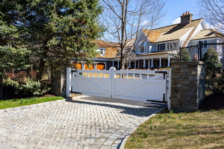 stone apron around a white wooden driveway gate with subtle finials