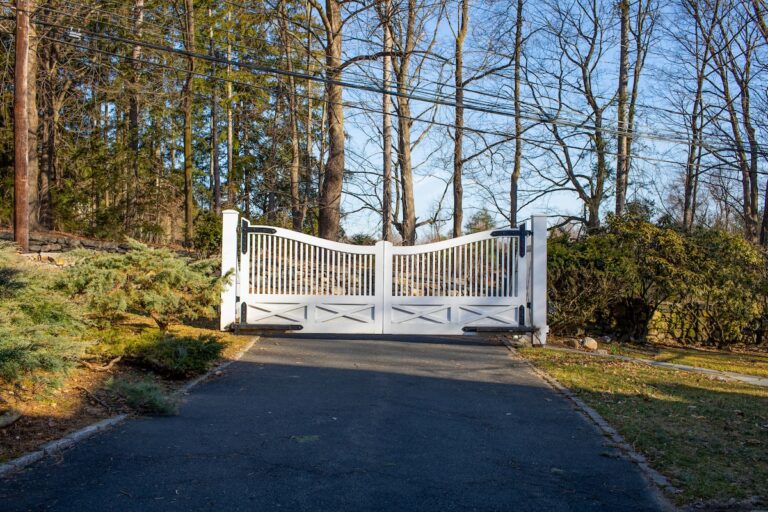 white scalloped wood driveway gate with black hardware