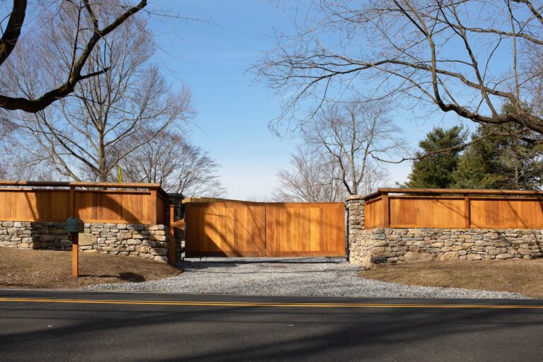 simple wood driveway gate with vertical slats and matching privacy fence with stone apron